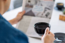 Blurred image of man reading newspaper holding coffee cup